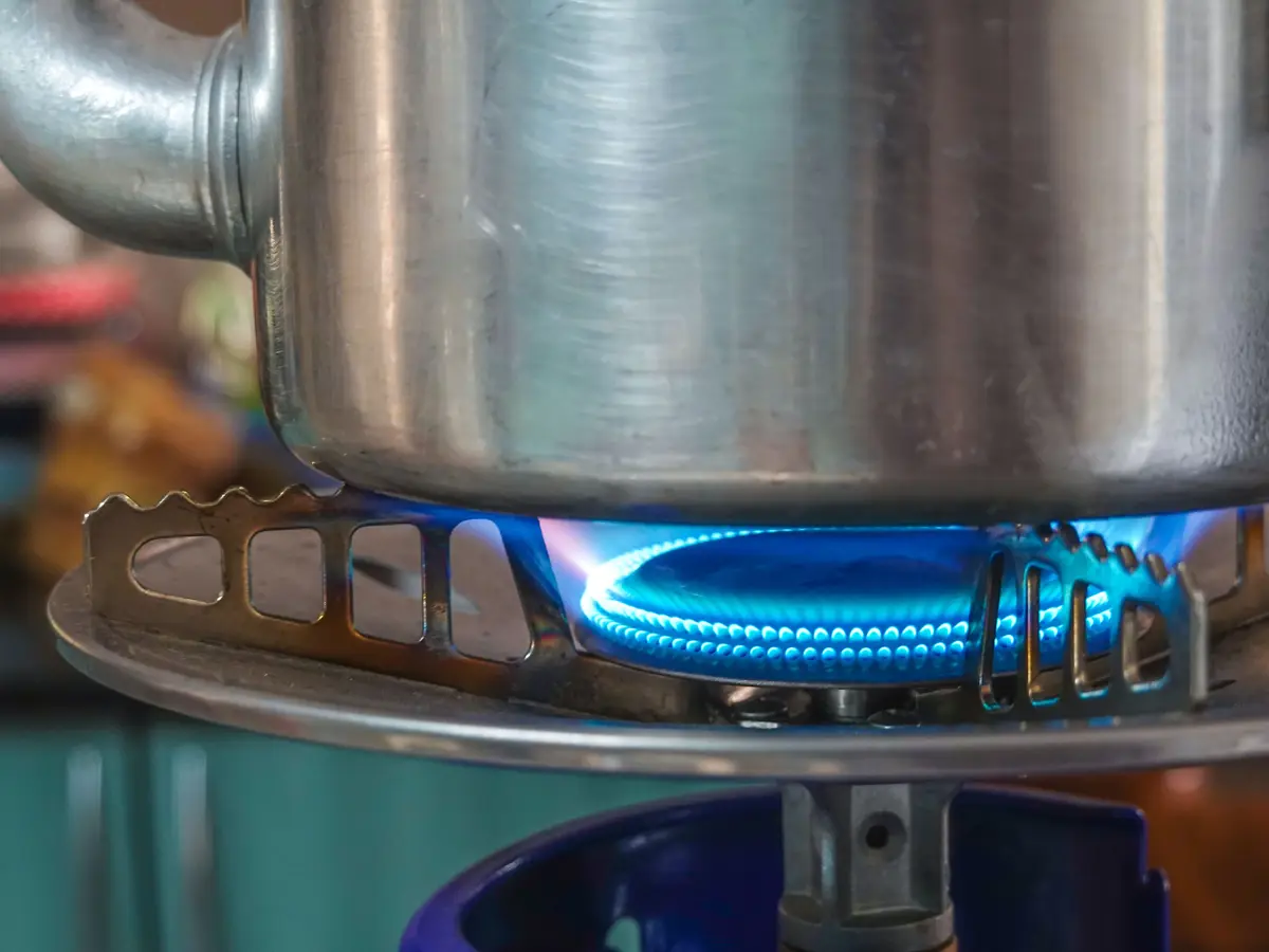 A clean blue flame on a gas hob ring under a steel pan