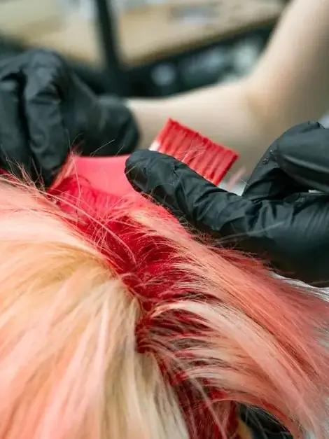 Vivid hair colour being applied by hand during a colour service