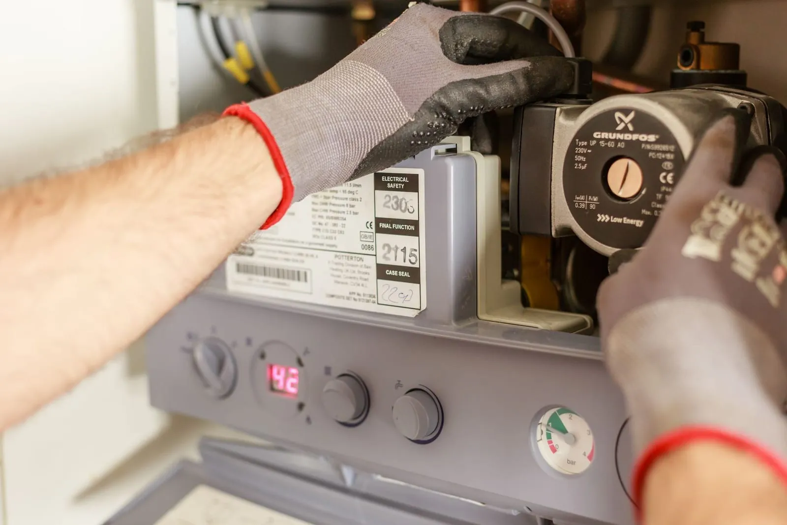 Plumber's gloved hands servicing a Potterton gas boiler