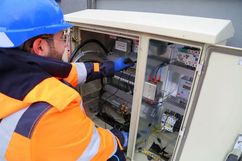 An electrician in hi-vis working inside an opened consumer unit